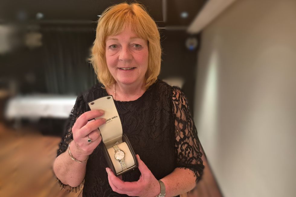 Gro Mette viser fram gullklokke hun har fått for 40 års tjeneste